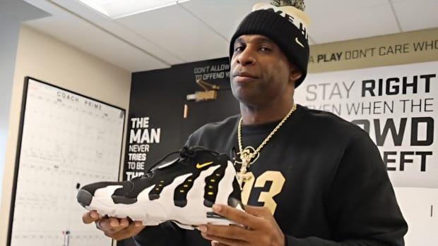 Deion Sanders holding Diamond Turf 3's in his office